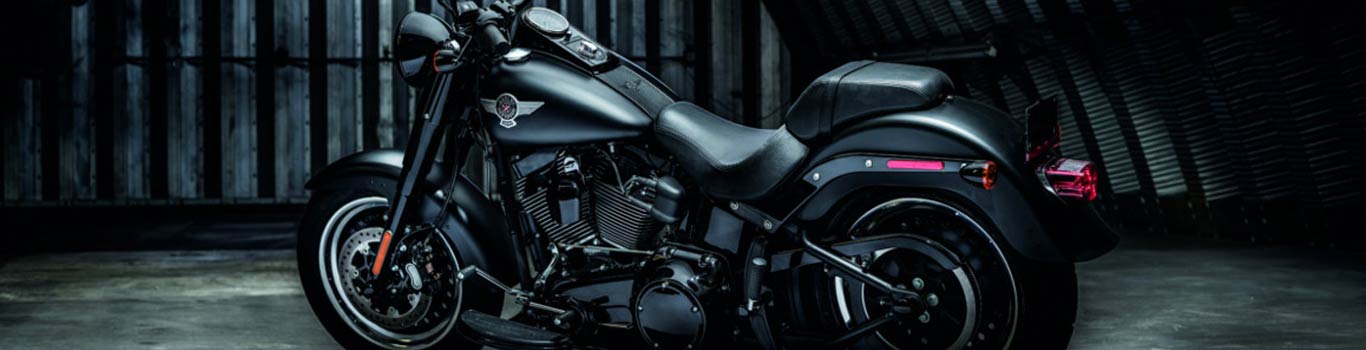 A close-up of a black  Harley-Davidson motorcycle in a dark garage.